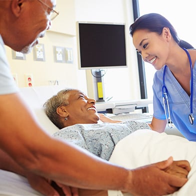 Smiling%20female%20medical%20practitioner%20attends%20to%20smiling%20patient%20in%20hospital%20bed