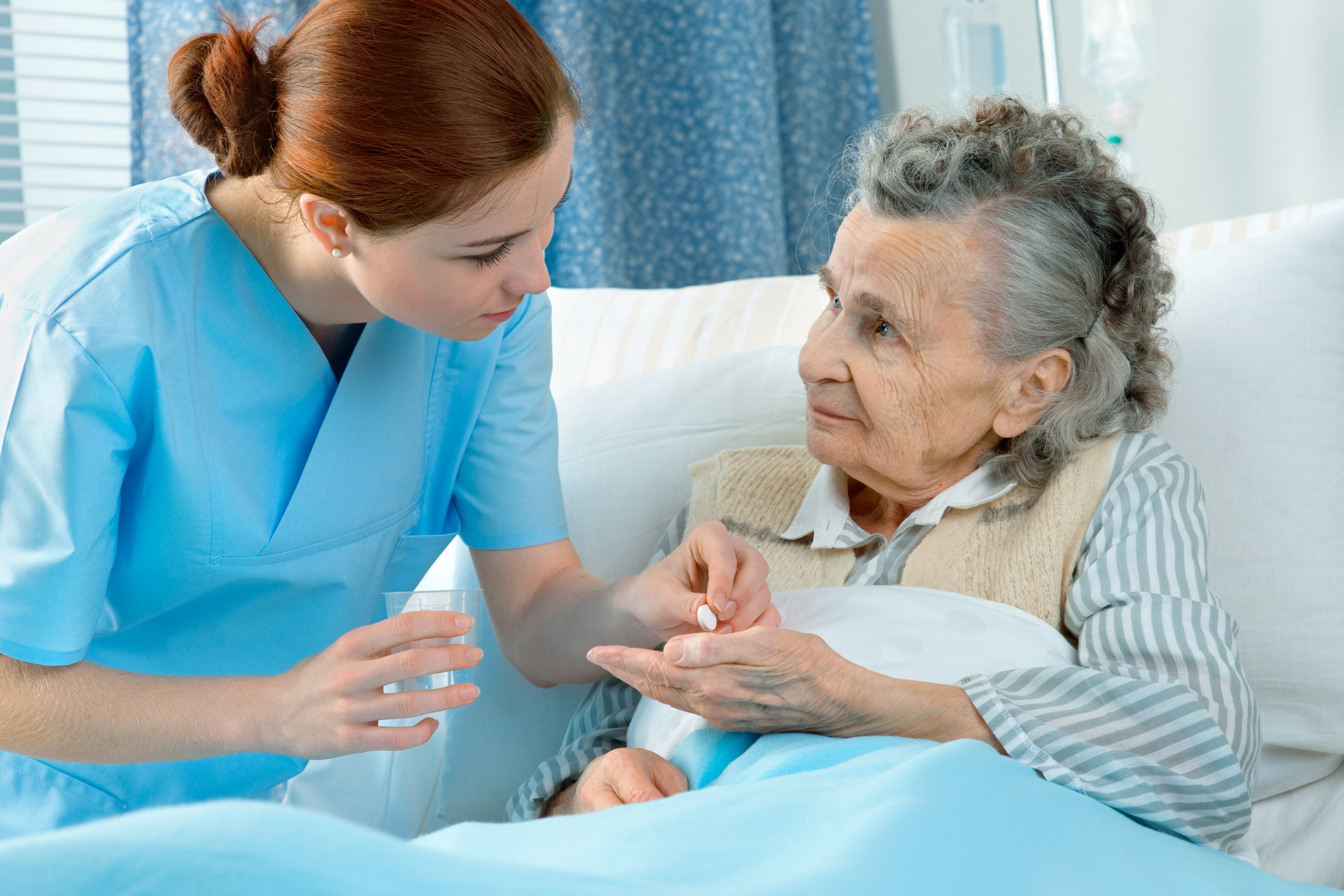 Nurse in blue scrub assisting a patient.