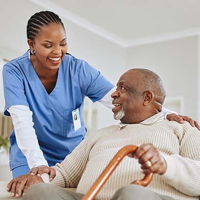 Nurse helps older man with cane