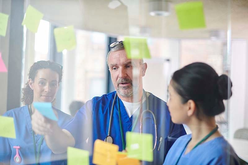 A group of people in scrubs looking at sticky notes