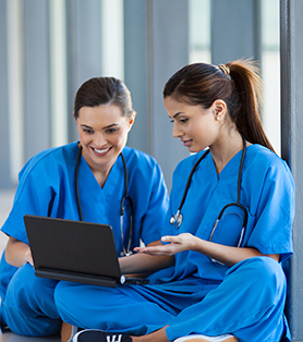 smiling nurses with a stethoscope and in blue scrub looking at a tablet